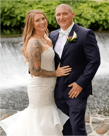 A man and woman posing for a picture in front of a waterfall.