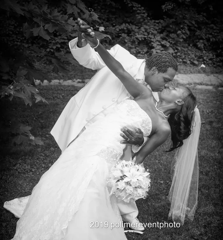 A bride and groom kissing in the grass.